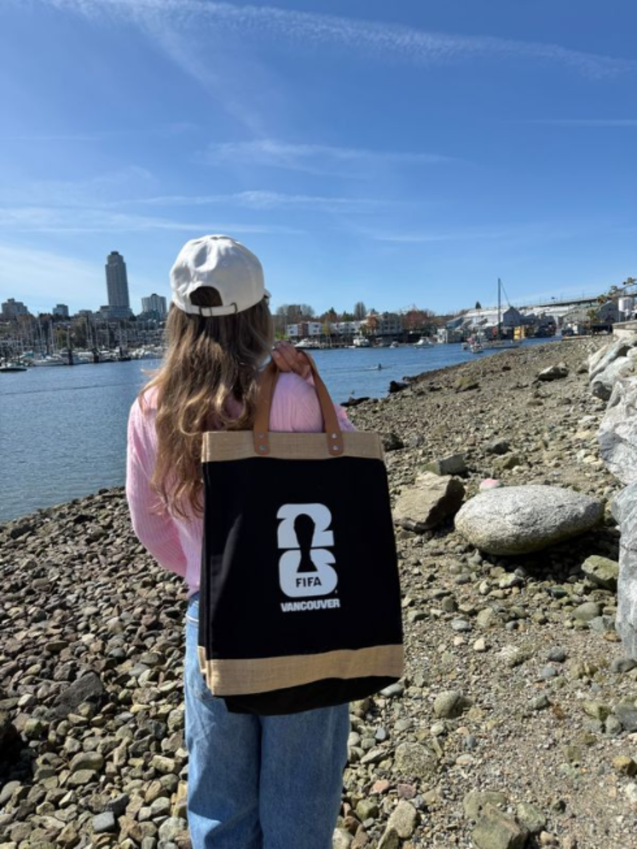 Person holding a canvas market bag with a FIFA Vancouver logo