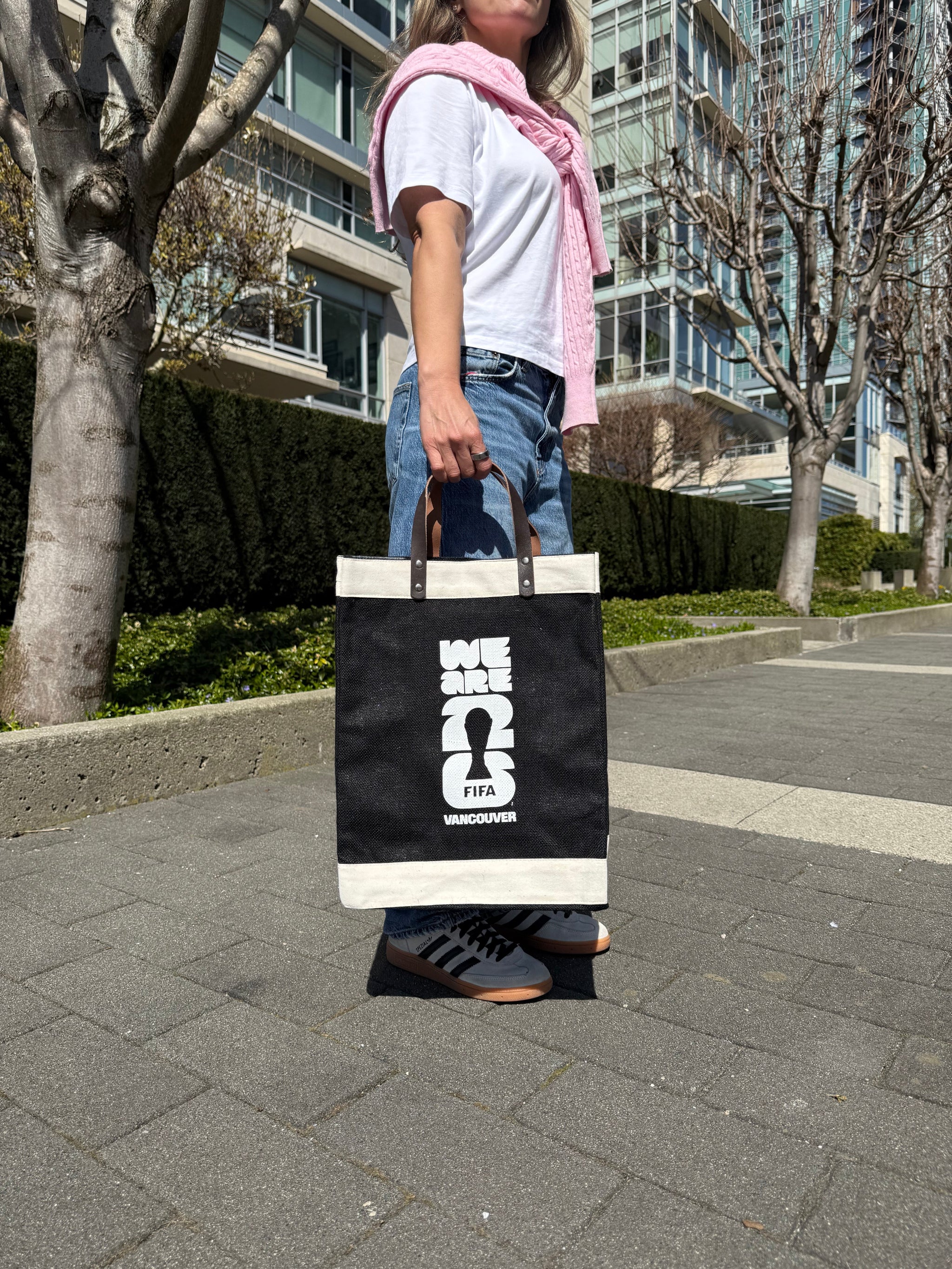 Person holding a black market bag with white text on a street.