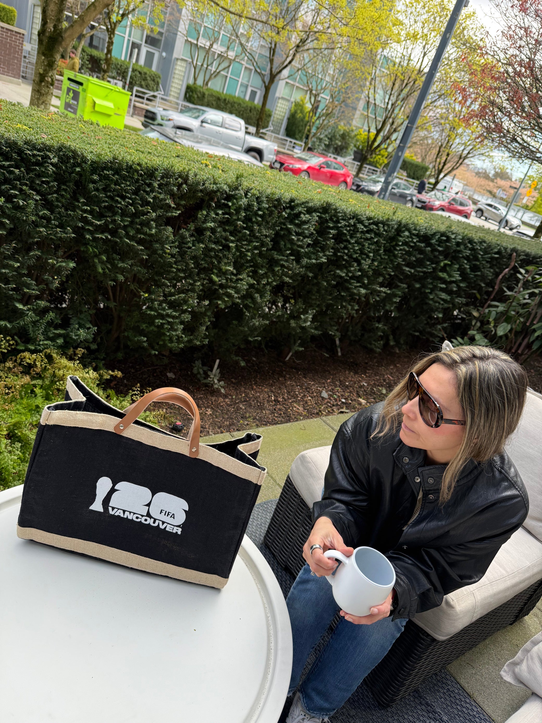 Woman sitting outdoors holding a mug with a market bag FIFA Vancouver 2026
