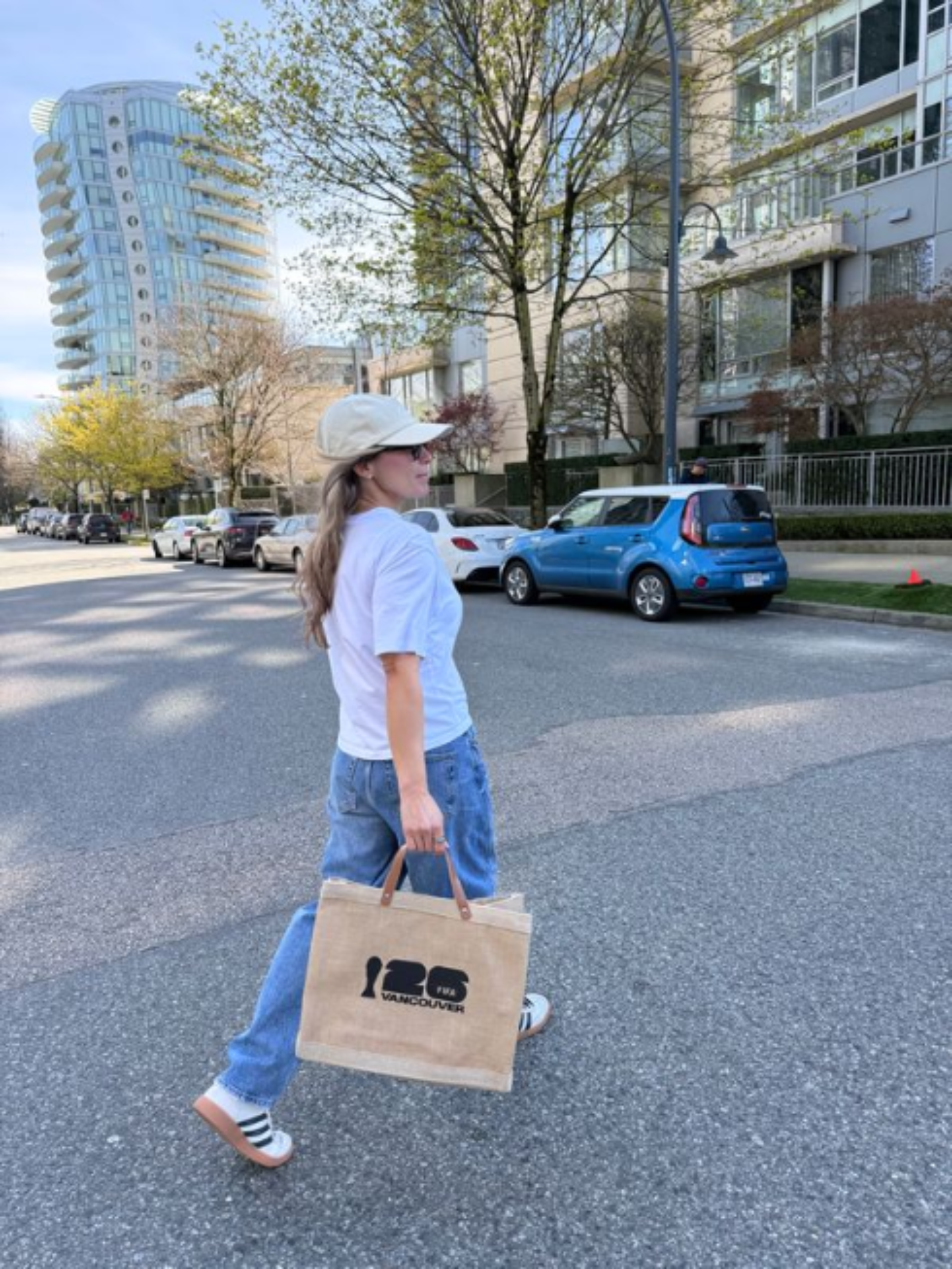 Person walking on a street holding a market bag with a FIFA Vancouver  logo