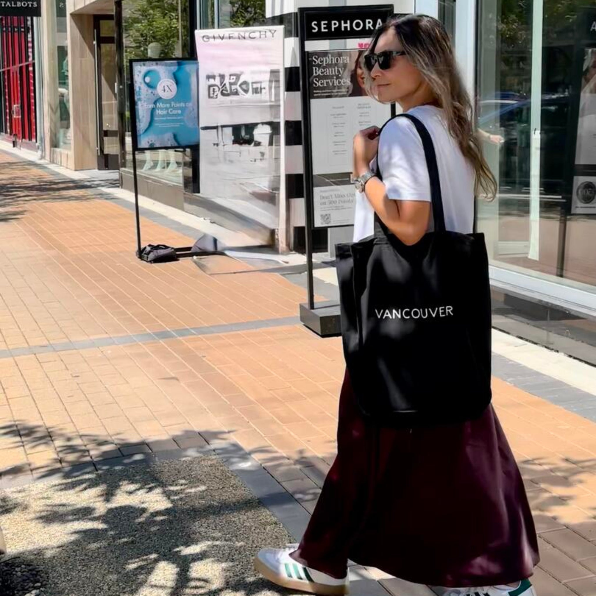 Woman walking on a sidewalk with a Sephora store in the background