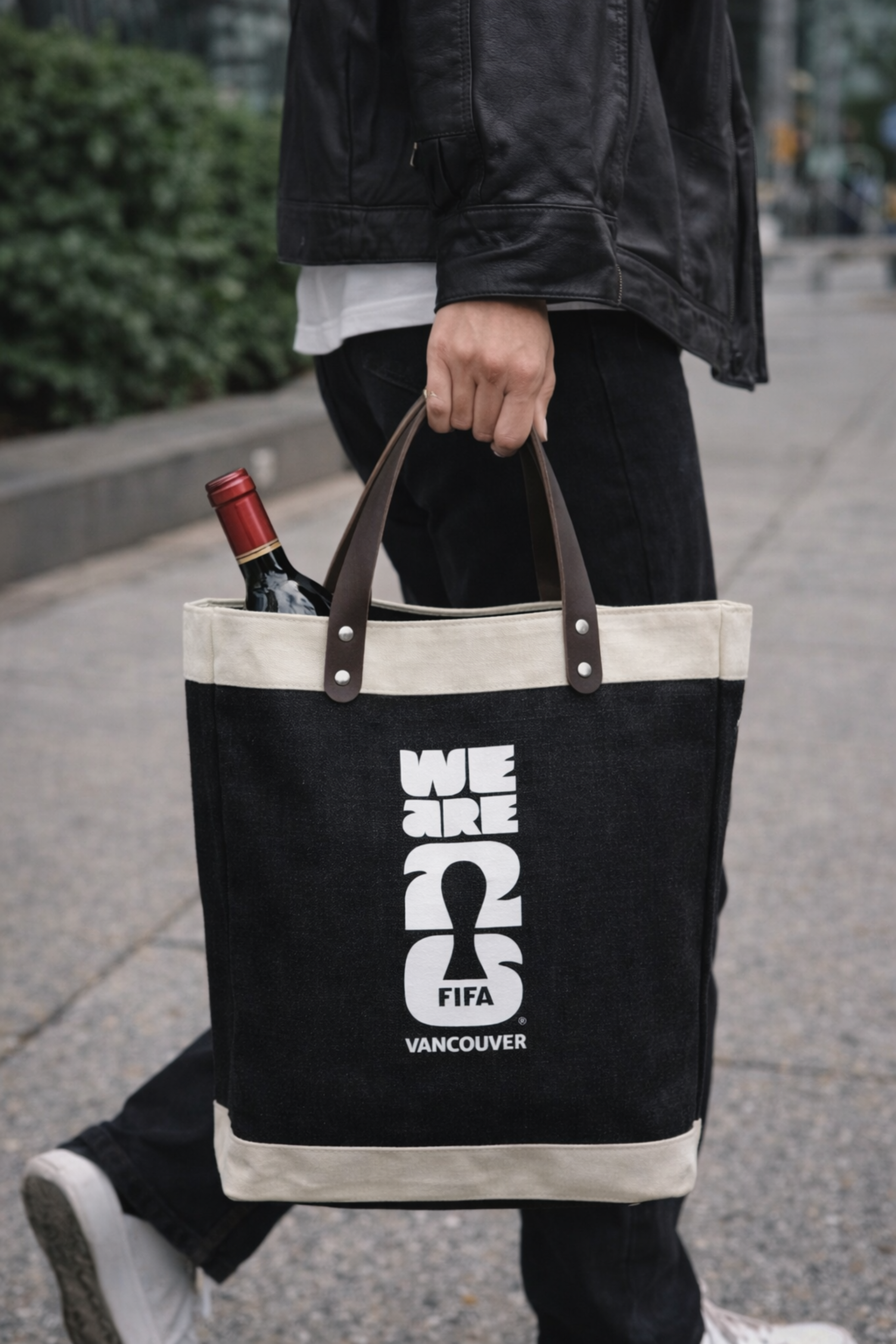Person holding a black tote bag with FIFA world cup Vancouver branding.